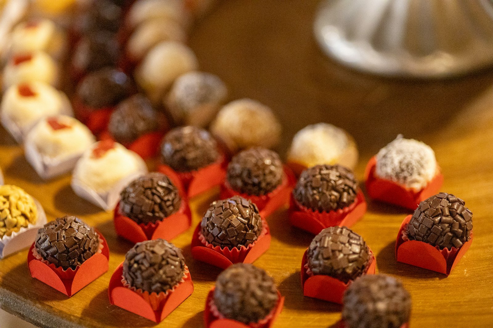 Brigadeiros e docinhos em forminhas vermelhas sobre a bancada, prontos para a encomenda